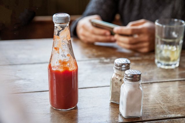An image of a ketchup bottle and salt and pepper shakers on a restaurant table