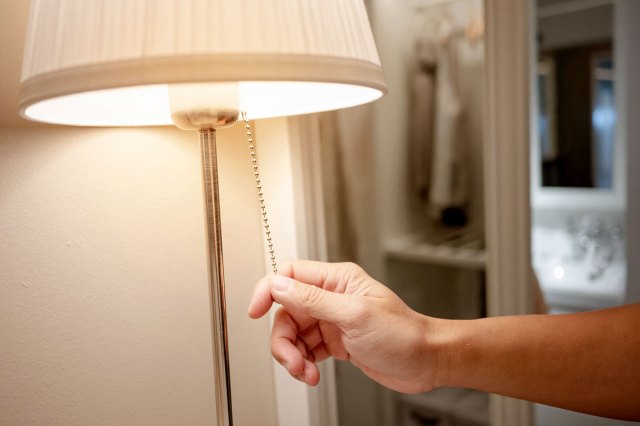 A close-up image of a person turning off a lamp