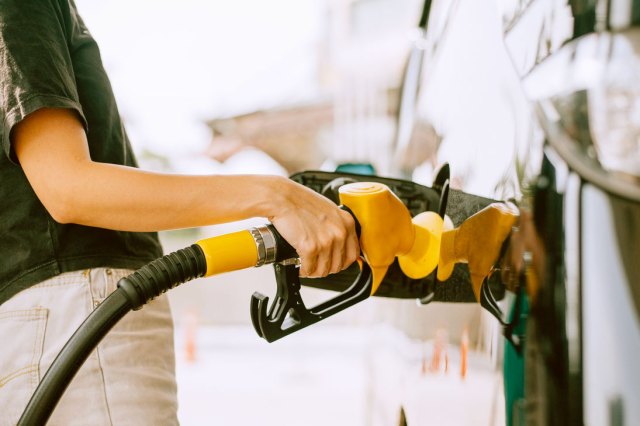 A close-up image of a person pumping gas into a car