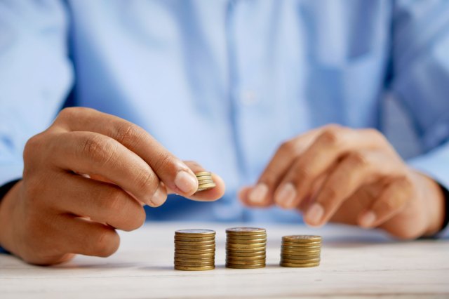 A man stacks coins in three piles