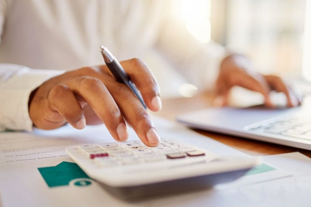 A close-up image of a person using a calculator