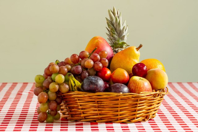 An image of a basket of fruit on a red and white checkered table cloth