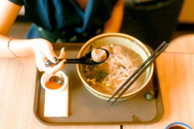 An image of a person taking a spoonful of pho soup