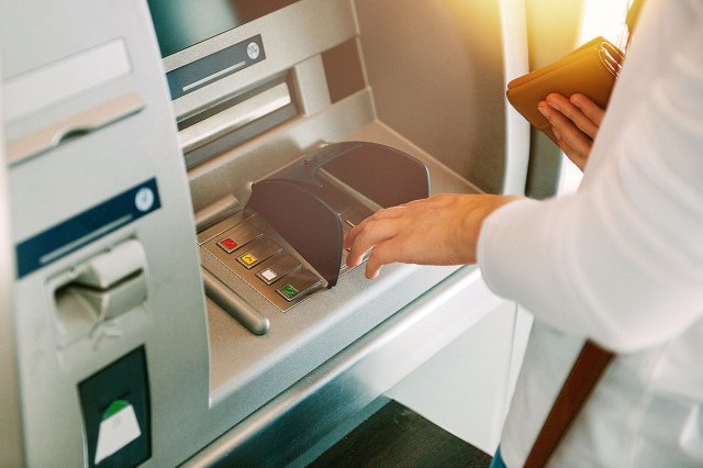 A close-up image of a person at an ATM