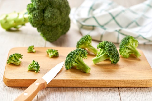 An image of broccoli on a wooden cutting board