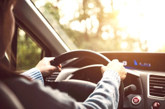 A person holding the steering wheel of a car