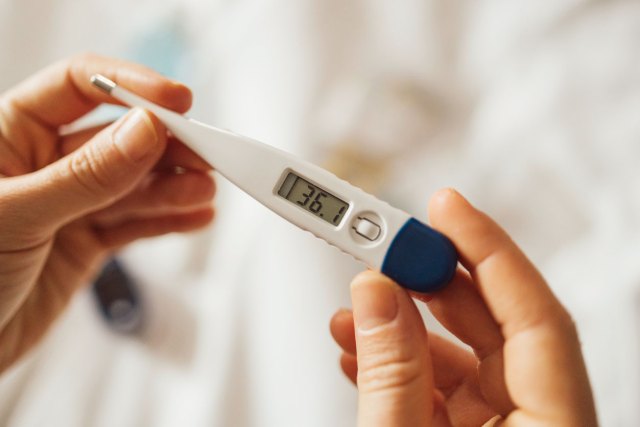An image of a person holding a thermometer