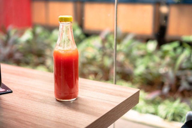 An image of a bottle of tobasco on a wooden outdoor table
