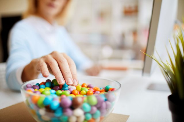 An image of a woman taking candy out of a candy bowl