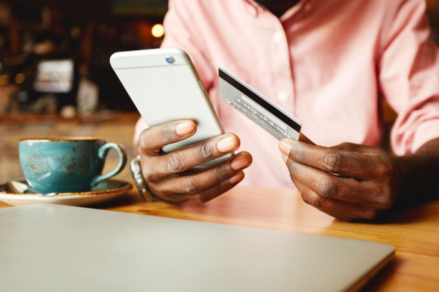 A man holding a credit card and a phone