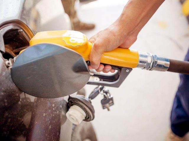 A close-up image of a person pumping gas