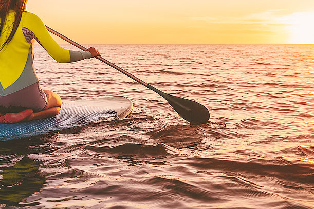 An image of a person on a paddle board in the ocean during sunset