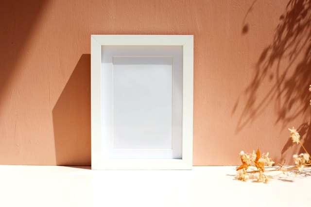 An image of a white picture frame against a brown wall