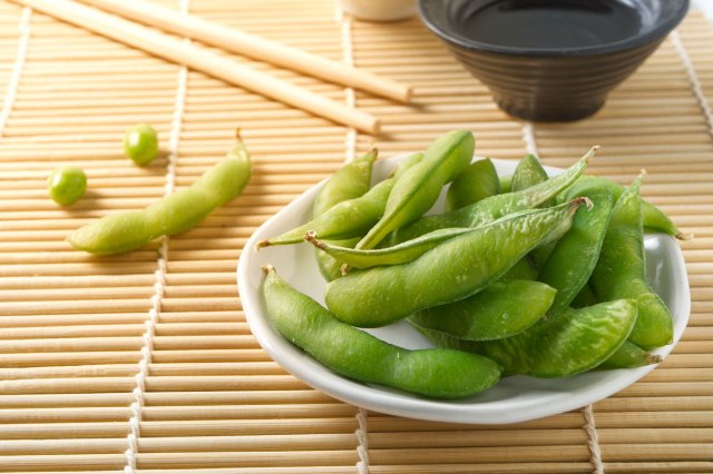 An image of a plate of edamame on a wooden placemat