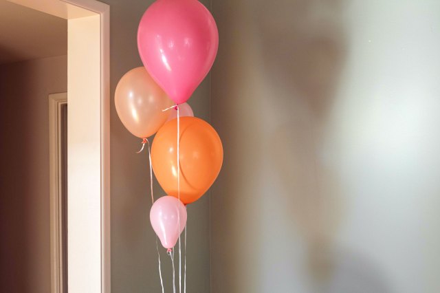 An image of different colored balloons in the corner of a room