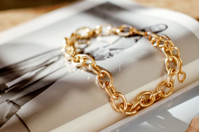 An image of a gold chain bracelet on top of a magazine spread
