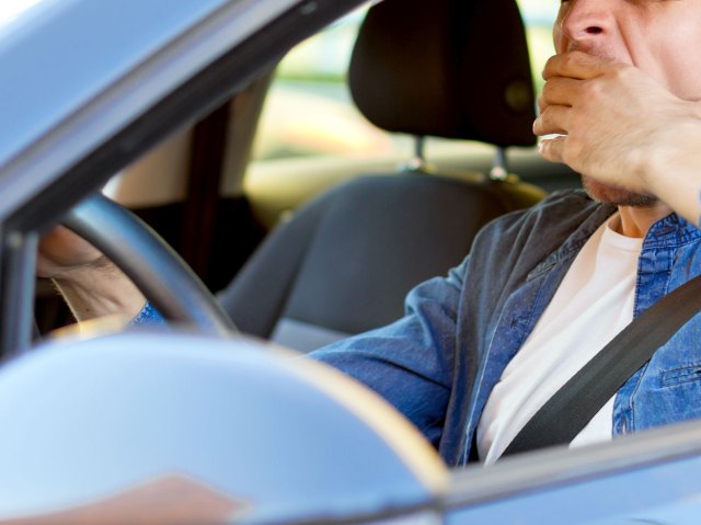 An image of a man yawning while driving