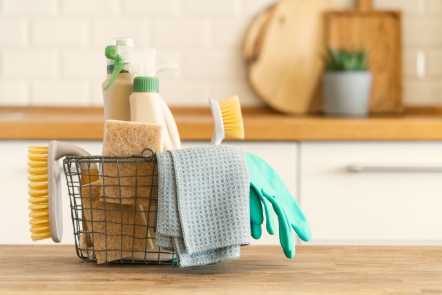 An image of a basket with brushes, rags, natural sponges and cleaning products