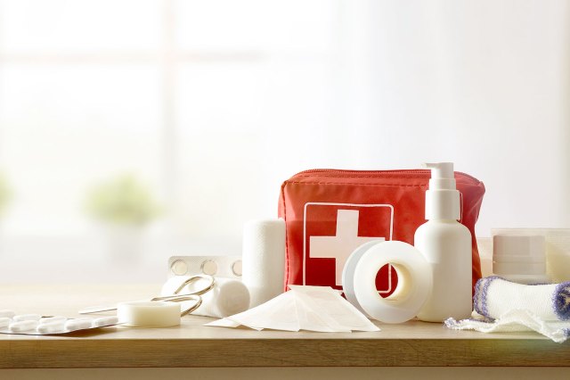 An image of a first aid kit and supplies on a wooden counter