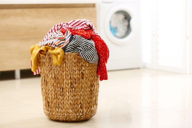 A wicker basket laundry hamper filled with clothes