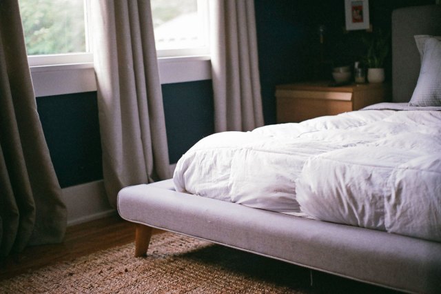 An image of a bed with a white comforter in a bedroom