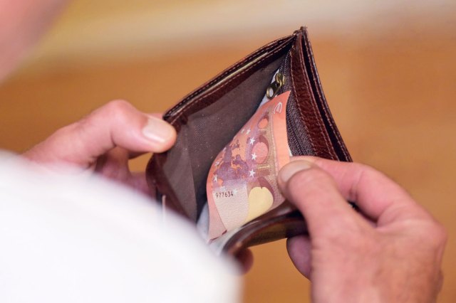 A close-up image of a hand taking money out of a wallet