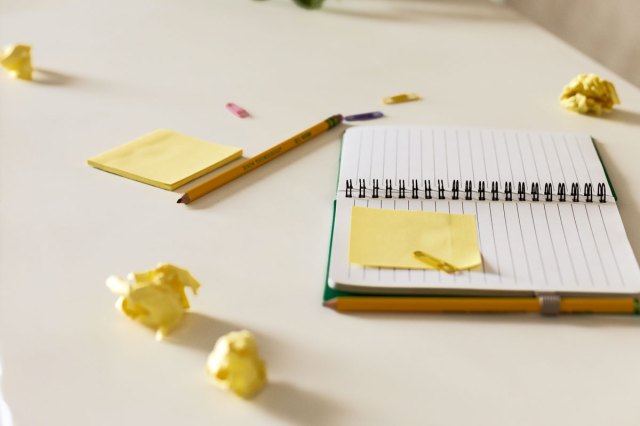 An open notebook surrounded by balled-up sticky notes
