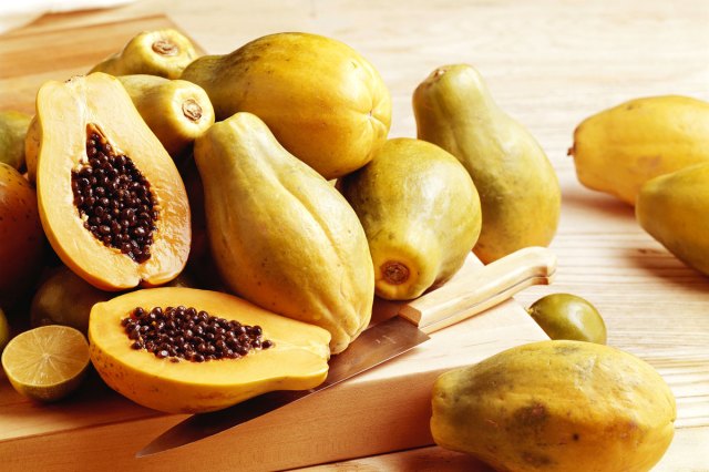 An image of papayas on a wooden cutting board