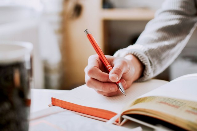 A person writes in an open journal