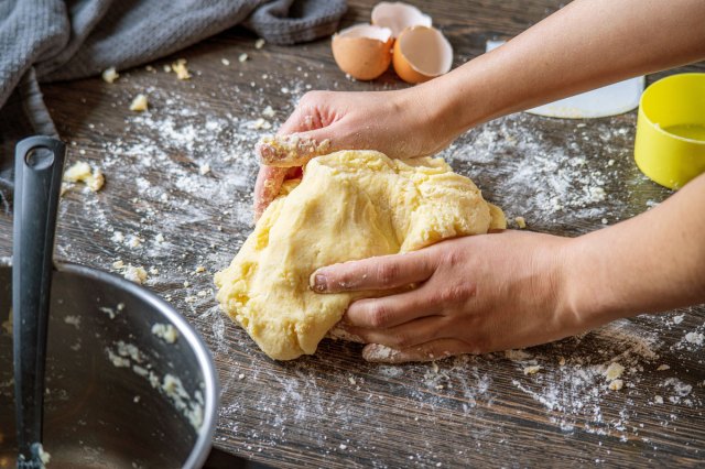 An image of a person kneading dough on a wooden counter