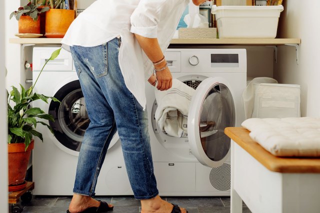 An image of a woman taking a white blanket out of the dryer