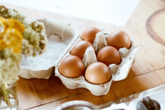 An image of a carton of brown eggs on a wooden counter