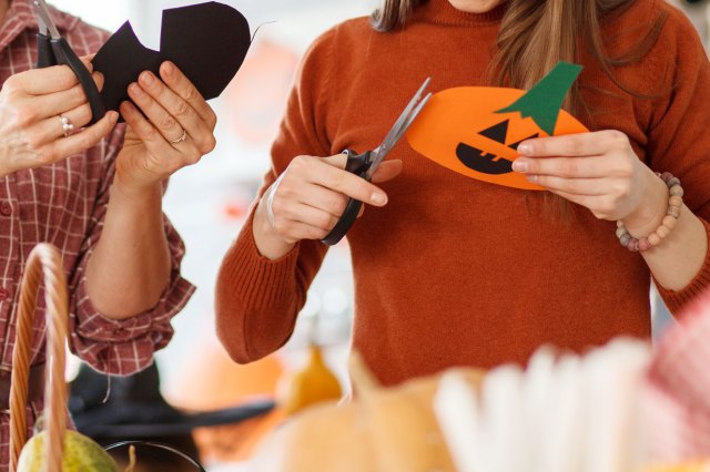 An image of a young woman and her mother cutting paper decorations for Halloween