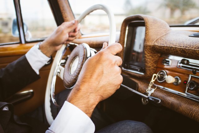 A person holds the steering wheel of a car
