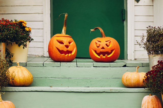 An image of two jack-o'-lanterns on a green porch
