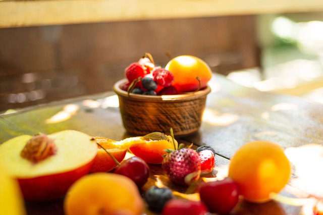 An image of a bowl of fruit on a wooden table with various fruit