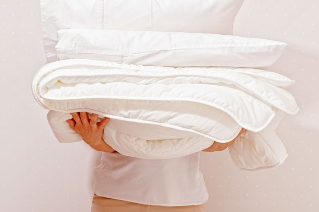 An image of a person holding a white comforter
