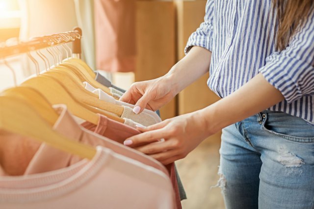 An image of a woman looking through a rack of clothes