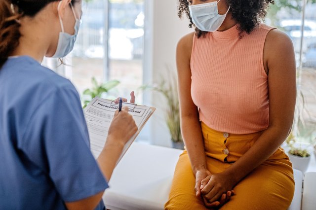 An image of a nurse talking to a woman sitting on an examining table