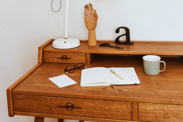 An open journal surrounded by other accessories on a wooden desk