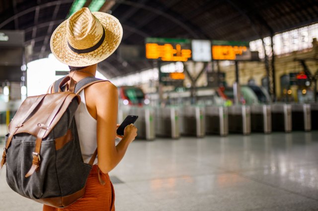 An image of a female traveler at the train station waiting for her train.