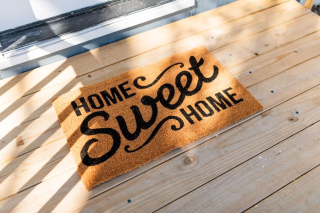 A welcome mat that reads "Home Sweet Home" on a wooden deck