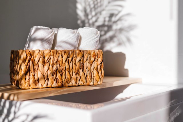 An image of a brown basket with white towels in it on a shelf