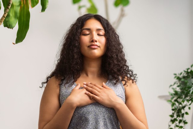 An image of a woman with her eyes close and hands folded on her chest