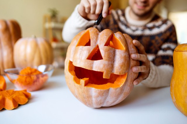 An image of a man carving a jack-o-lantern