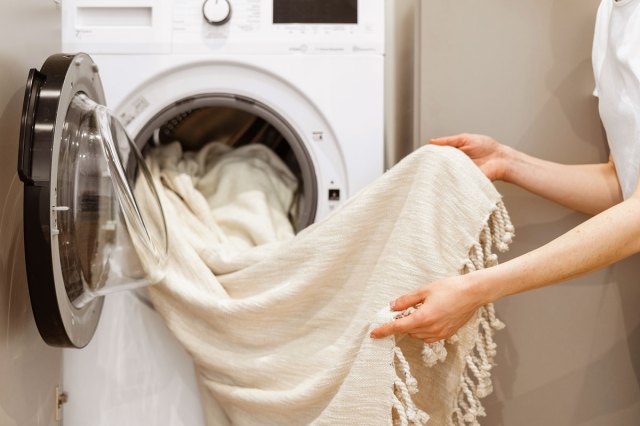 An image of a person taking a white blanket out of the dryer
