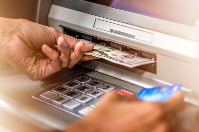 An image of a person taking money out of an ATM