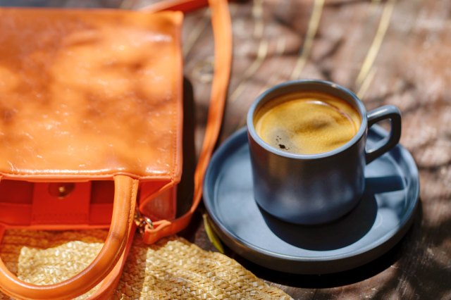 An image of a cup of coffee and a purse on a table