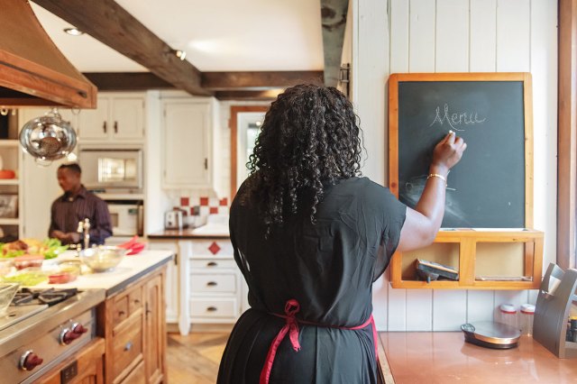 An image of a woman writing a men on a chalkboard in a kitchen