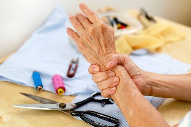 A person holding their wrist over sewing supplies on a table